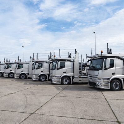Group of trucks parked in line at truck stop.